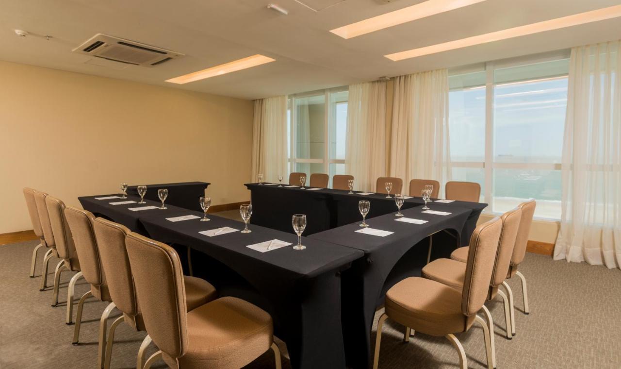 Hotel Luzeiros Sao Luis Экстерьер фото The photo shows a conference or meeting room set up for a presentation or discussion. It features several tables arranged in a U-shape, covered with black tablecloths. Each table has a glass of water and a napkin placed in front of each chair. The ro